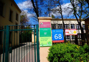 Zielona furtka i tablice z napisami:Przedszkole Miejskie nr 220, Polskie Stowarzyszenie Montessori, Żłobek Montessori oraz tabliczka z adresem ul.Jaracza 68