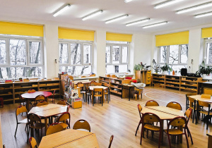 Klasa przedszkolna- z tyłu okna, dookoła szafki z pomocami na środku stoły z krzesłami