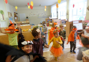 Dzieci z grupy 3 tańczą na balu jesieni. Przebrane są kolorowo w kolorach jesieni.