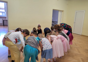Przedszkolaki tańczą w kole trzymając się za kolana-zabawa tańczymy Labada