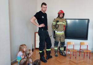 Strażacy opowiadają o swojej pracy , dzieci siedzą na podłodze.