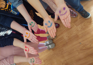 Dzieci pokazują prawą rękę z namalowaną buzią.