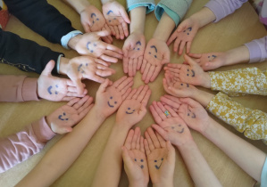 Dzieci pokazują dwie dłonie z namalowanymi buziami.