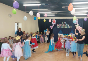 Dzieci znajdują się na sali gimnastycznej. Na środku sali przechodzą po kole dzieci z grupy 1 pokazując stroje królewskie.