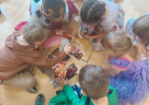 Sześcioro dzieci układają z puzli na podłodze portret króla Bolesława Chrobrego