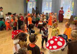 Dzieci stoją w kołach w swoich grupach i słuchają co będą wykonywać. Pani Karolina objaśnia zadanie na tablicy.